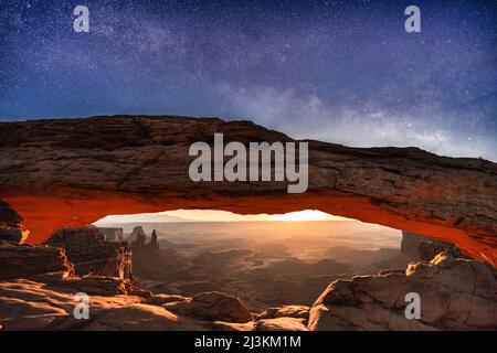 Una rara immagine della via lattiginosa e della luna che si innalza per illuminare il paesaggio desertico sotto Mesa Arch, Parco Nazionale Canyonlands Foto Stock
