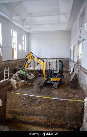 Stralsund, Germania. 28th Mar 2022. Jörg Ansorge, archeologo, scavando con un escavatore su un muro di mattoni in una ex palestra sui terreni del monastero di Santa Caterina. I reperti si trovano all'interno dell'ex monastero di San Katharinen, nella città vecchia di Stralsund. Gli edifici ospitano, tra gli altri, il Museo Marittimo, attualmente in fase di ristrutturazione. I reperti saranno resi accessibili ai visitatori in futuro. Credit: Stefan Sauer/dpa/Alamy Live News Foto Stock