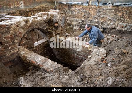 Stralsund, Germania. 28th Mar 2022. Jörg Ansorge, archeologo, pulisce un muro di cantina in mattoni in una ex palestra sui terreni del monastero di Santa Caterina. I reperti si trovano all'interno dell'ex monastero di San Katharinen, nella città vecchia di Stralsund. Gli edifici ospitano, tra gli altri, il Museo Marittimo, attualmente in fase di ristrutturazione. I reperti saranno resi accessibili ai visitatori in futuro. Credit: Stefan Sauer/dpa/Alamy Live News Foto Stock