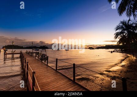 Vista della Baia di Samana da un molo al tramonto con barche ormeggiate nel porto lungo le rive di Samana; Penisola di Samana, Repubblica Dominicana, Caraibi Foto Stock