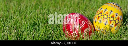 Due uova di Pasqua dipinte a mano giacciono nell'erba Foto Stock