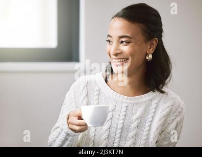 Posso finalmente dire che l'ho fatto. Scatto di una giovane donna attraente seduta da sola nella sua nuova casa e godere di una tazza di tè. Foto Stock