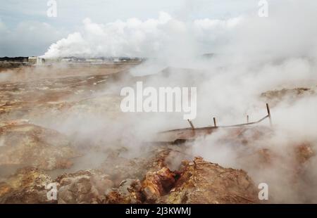 Campo geotermico di Gunnuhver, con un impianto geotermico alle spalle, Islanda; Reykjanesviti, penisola di Reykjanes, Islanda. Foto Stock