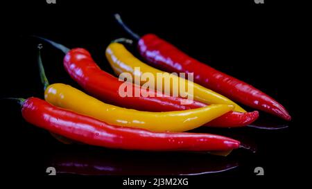 Peperoncini Chili su sfondo nero. Peperoncino caldo fresco rosso e giallo. Foto Stock