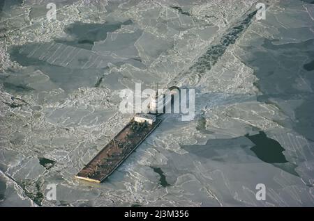 Tugboat pushing barge through winter ice on the Chesapeake Bay.; CHESAPEAKE BAY, MARYLAND. Foto Stock