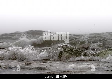 Primo piano di un'onda in avvicinamento che si infrangono sulla riva con un cielo coperto bianco; South Shields, Tyne and Wear, Inghilterra Foto Stock