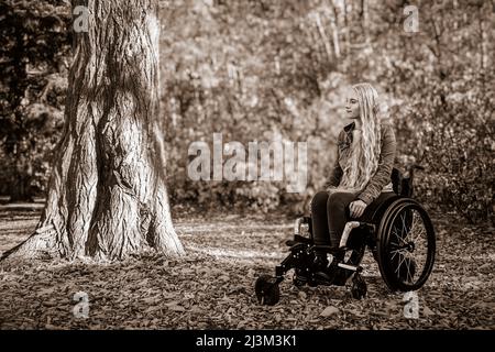 Una giovane paraplegica in sedia a rotelle in un parco in una bella giornata autunnale; Edmonton, Alberta, Canada Foto Stock