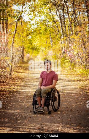 Ritratto di un paraplegico in una sedia a rotelle all'aperto in un parco in autunno; Edmonton, Alberta, Canada Foto Stock