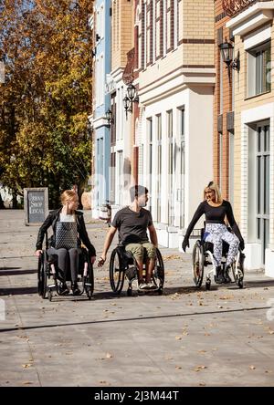 Tre giovani amici paraplegici trascorrono del tempo insieme facendo shopping fuori in una zona della città; Edmonton, Alberta, Canada Foto Stock