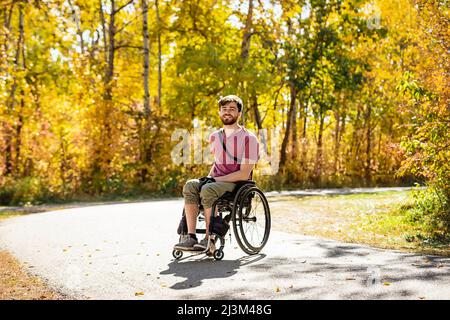 Ritratto di un paraplegico in una sedia a rotelle all'aperto in un parco in autunno; Edmonton, Alberta, Canada Foto Stock