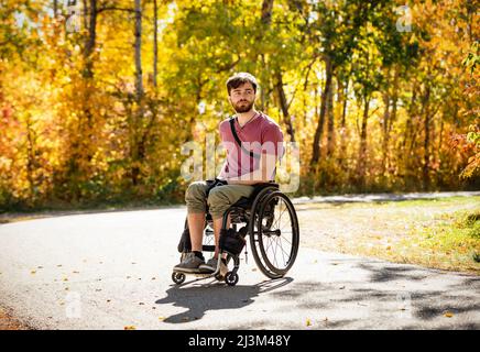 Ritratto di un paraplegico in una sedia a rotelle all'aperto in un parco in autunno; Edmonton, Alberta, Canada Foto Stock