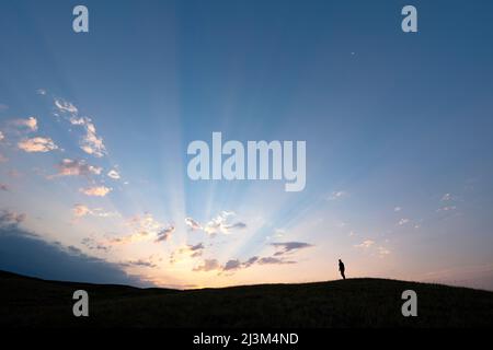 Persona con sagome che guarda l'alba sulle praterie nella campagna Saskatchewan, Grasslands National Park; Saskatchewan, Canada Foto Stock