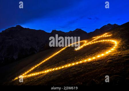 La costruzione e l'illuminazione di un fuoco di cuore sacro sul monte Elferspitze nella valle dello Stubai.; Austria. Foto Stock