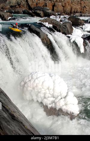 Un kayak invernale in acqua bianca sul bordo di una grande cascata e ghiaccio.; Great Falls, Potomac River, Maryland. Foto Stock