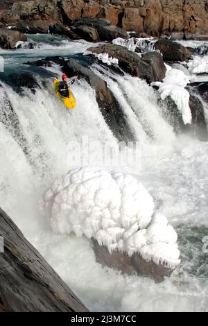 Kayak invernale in acqua bianca sul bordo di una grande cascata con ghiaccio.; Great Falls, Potomac River, Maryland. Foto Stock