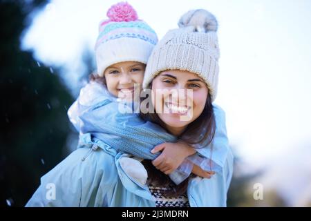 Niente batte giocare sotto la pioggia. Scatto di una giovane donna attraente che dà a sua figlia un giro di piggyback fuori sotto la pioggia. Foto Stock