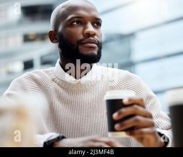 Il caffè suscita tutti i pensieri ambiziosi. Scatto di un giovane uomo d'affari che guarda premuroso mentre beve il caffè fuori di un ufficio. Foto Stock