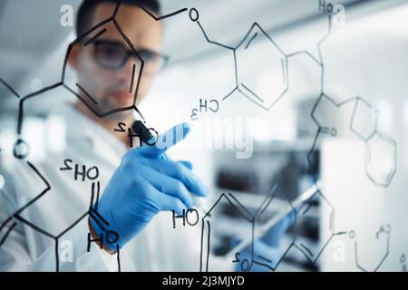 L'uomo della scienza con un piano. Scatto di un giovane scienziato che risolve le equazioni su uno schermo di vetro in un laboratorio. Foto Stock