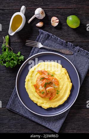 Polenta e schie fritte, piatto veneziano, polenta con gamberi fritti su un piatto su tavola di legno scuro con aglio una salsa sullo sfondo, vista verticale da Foto Stock