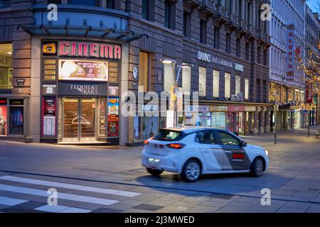 Stoccarda, Germania - 06 gennaio 2022: Cinema di città a Stoccarda. Ingresso con porta la mattina presto. Sfocatura del movimento dell'auto. Foto Stock