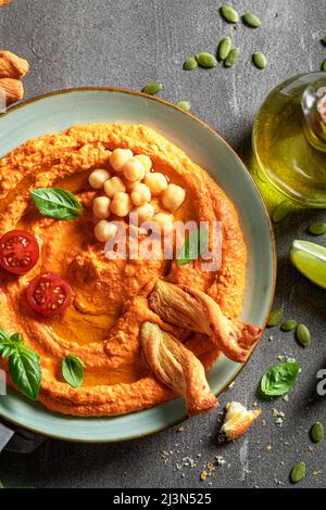 Vegano e hummus di pomodoro fatto in casa come snack sano e veloce. Hummus al pomodoro servito con grissini e olio d'oliva. Foto Stock