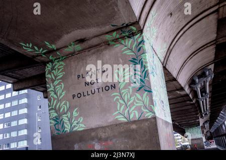 Sotto la struttura in cemento, un'opera d'arte che annuncia "piante non inquinate" è stata scritta su un pilastro del cavalcavia di Hammersmith, il 6th aprile 2022, a Londra, in Inghilterra. Foto Stock