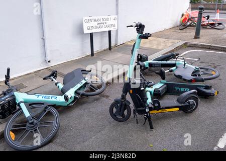 Durante una giornata ventosa nella capitale, il 6th aprile 2022, a Londra, Inghilterra, si sono abbattuti un noleggio di biciclette e un eScooter rossi su Glentham Road, Barnes, vicino a Hammersmith Bridge, ora chiuso al traffico automobilistico ma aperto ai pedoni. Foto Stock