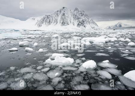 Fine estate, mare e paesaggio all'interno del cerchio Antartico, con i turisti in uno Zodiaco in lontananza. Al largo di Neny Island all'interno della baia di Marguerite Foto Stock