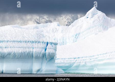 Da vicino iceberg con montagne sullo sfondo, Marguerite Bay, Antartide Foto Stock