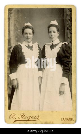 Donna vittoriana degli anni '1890 Originale e trasparente CDV vittoriano (carte de visite o biglietto da visita) di 2 / due attraenti cameriere vittoriane, servitore vittoriano, indossando grembiuli bianchi amalgamati, cappellini, camicette con la 'gamba di maniche di montone' alla moda a metà degli anni '1890 Dallo studio fotografico di Archibald Rogers, Lanark, South Lanarkshire (Clydesdale) Scotland, U.K. circa 1895 Foto Stock