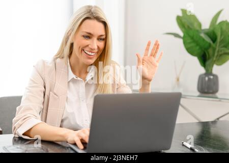 Felice giovane bella donna guardando lo schermo del laptop, tenendo videochiamata riunione conversazione, discutere di problemi di lavoro, passare intervista di lavoro da casa. Concetto di comunicazione a distanza Foto Stock