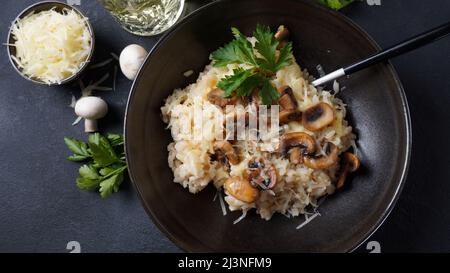 Risotto ai funghi guarnito con prezzemolo e parmigiano. Foto Stock