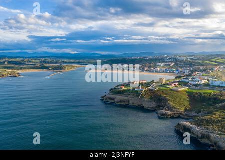 Vista aerea della città costiera, della spiaggia sabbiosa e delle scogliere lungo la costa cantabrica nel nord della Spagna, delle calme acque atlantiche e della luce serale Foto Stock