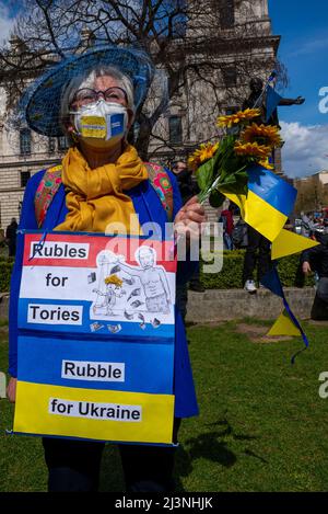 Parliament Square, Westminster, Londra, Regno Unito. 9th Apr 2022. Una protesta si sta svolgendo a sostegno dell'Ucraina nella guerra contro l'invasione russa. I manifestanti hanno tenuto cartelloni e striscioni con slogan. Donna con visti slogan sulla maschera e Tory Party - cartellone finanza russa Foto Stock