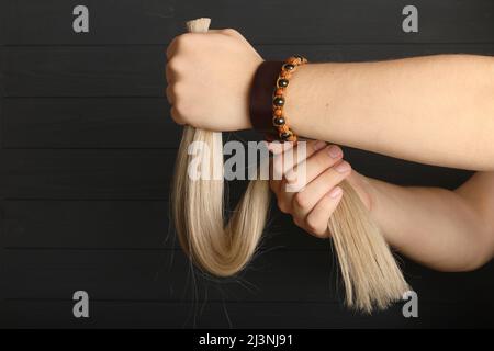 La mano maschio tiene le sezioni di capelli per l'estensione. Foto Stock