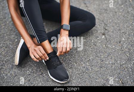 Ho ottenuto farli stretto. Closeup shot di una donna sportiva che lega le sue scarpe mentre si esercita all'aperto. Foto Stock