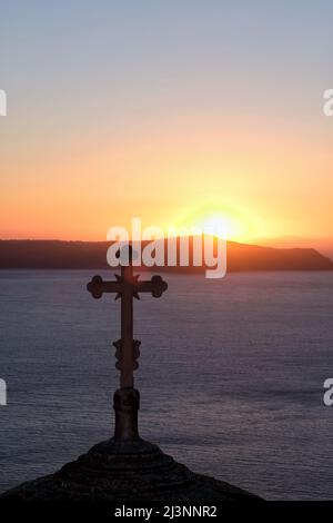 Vista di una chiesa ortodossa religiosa e una croce sulla cima, mentre il sole tramonta in modo spettacolare Foto Stock