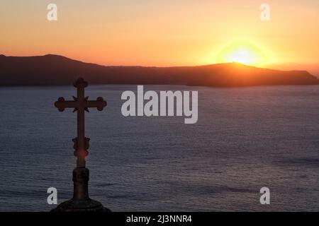 Vista di una chiesa ortodossa religiosa e una croce sulla cima, mentre il sole tramonta in modo spettacolare Foto Stock