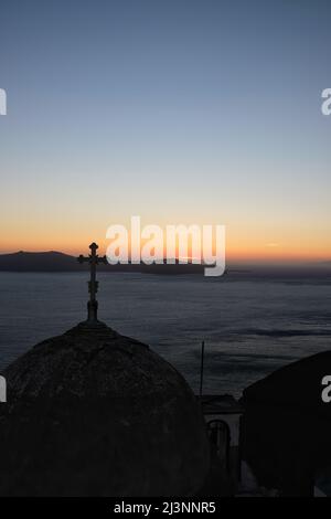 Vista di una chiesa ortodossa religiosa e una croce sulla cima, mentre il sole tramonta in modo spettacolare Foto Stock
