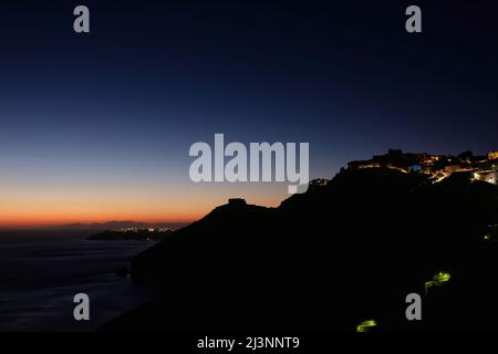 Vista panoramica del villaggio illuminato di Fira, Oia e uno spettacolare tramonto a Santorini Foto Stock