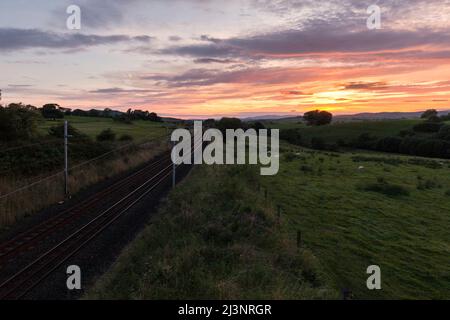 Linea ferroviaria principale della costa occidentale a Grayrigg Cumbria con il tramonto Foto Stock