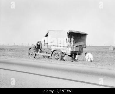 Famiglia tra Dallas e Austin, Texas. La gente ha lasciato la propria casa e le connessioni nel Texas meridionale, e spera di raggiungere il Delta dell'Arkansas per lavoro nei campi di cotone. Persone senza penniless. Non c'è cibo e tre galloni di gas nel serbatoio. Il padre sta cercando di riparare uno pneumatico. Tre bambini. Padre dice: "È difficile, ma la vita è dura comunque tu la prendi". Foto Stock