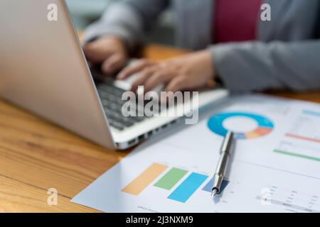 Business analista concetto la donna ufficiale digitando informazioni finanziarie sul computer portatile. Foto Stock