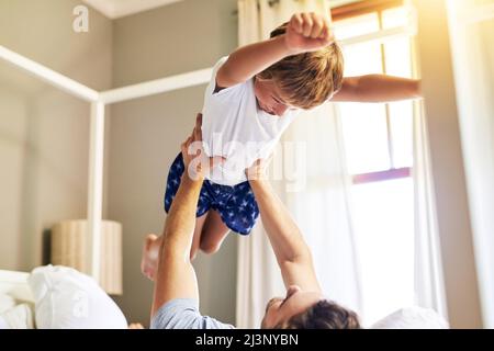 È il momento di volare. Sparato di un ragazzino allegro che viene preso dal padre mentre gioca in giro a casa la mattina. Foto Stock