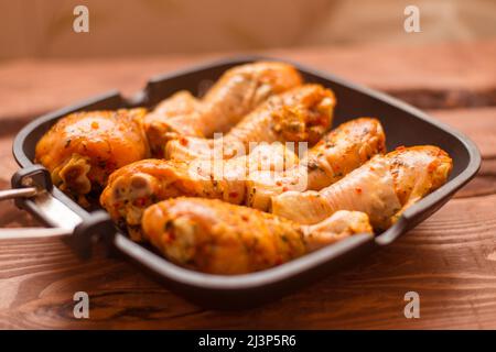 Bastoncini di pollo crudi in salsa e spezie in una padella non un fondo di legno. Foto Stock