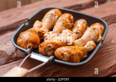 Bastoncini di pollo crudi in salsa e spezie in una padella non un fondo di legno. Foto Stock