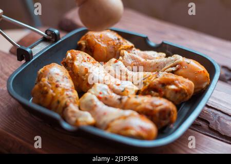 Bastoncini di pollo crudi in salsa e spezie in una padella non un fondo di legno. Foto Stock
