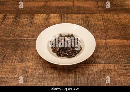 Spaghetti nero di seppia al frutti di mare. Ricetta di pasta della cucina italiana con un sapore sublime e intenso del mare Foto Stock