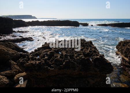 Ripide scogliere con un mare blu profondo e un cielo blu chiaro Foto Stock