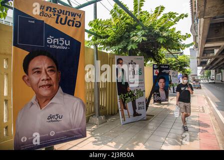 Un pedone passa accanto ai poster della campagna elettorale del governatore di Bangkok che mostrano i candidati Aswin Kwanmuang, Sakontee Pattiyakul e Suchatvee Suwansawat durante i preparativi per le prossime elezioni gubernatorial e consigliere della città di Bangkok. L'undicesima elezione del governatorato di Bangkok si terrà il 22 maggio 2022, che è la prima elezione del governatorato di Bangkok in nove anni dal 2013, dopo che l'esercito ha conquistato il potere in un colpo di stato del 2014. Foto Stock